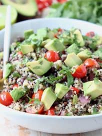 White bowl filled with quinoa salad with diced avocado and tomatoes