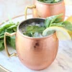 Copper mugs with moscow mules with fresh basil and lemon wedges