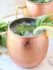 Copper mugs with moscow mules with fresh basil and lemon wedges
