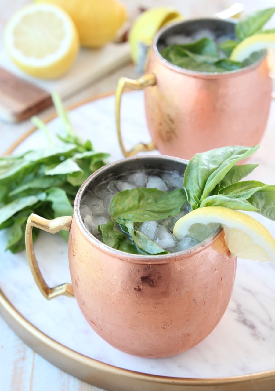 Moscow mule in copper mugs with fresh basil and lemon wedge on the side