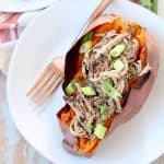 Pulled pork stuffed in roasted sweet potato on plate with fork