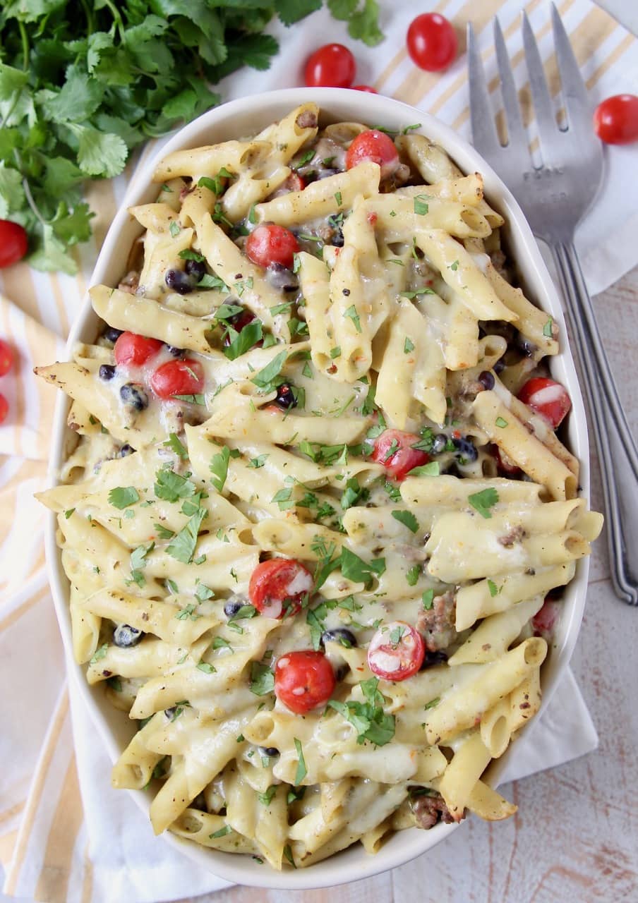 Taco pasta in a large oval casserole dish topped with cherry tomatoes and cilantro