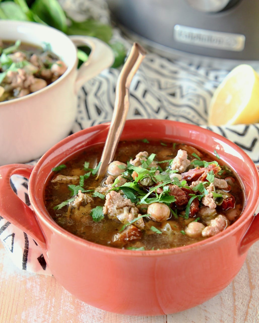 Greek turkey soup with chickpeas and spinach in orange bowl with copper spoon