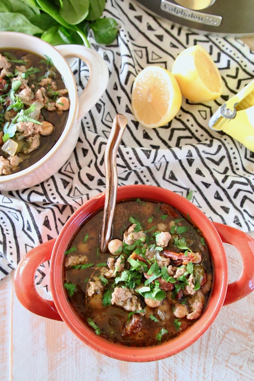 Ground turkey soup with chickpeas and spinach in bowls with sliced lemon on the side