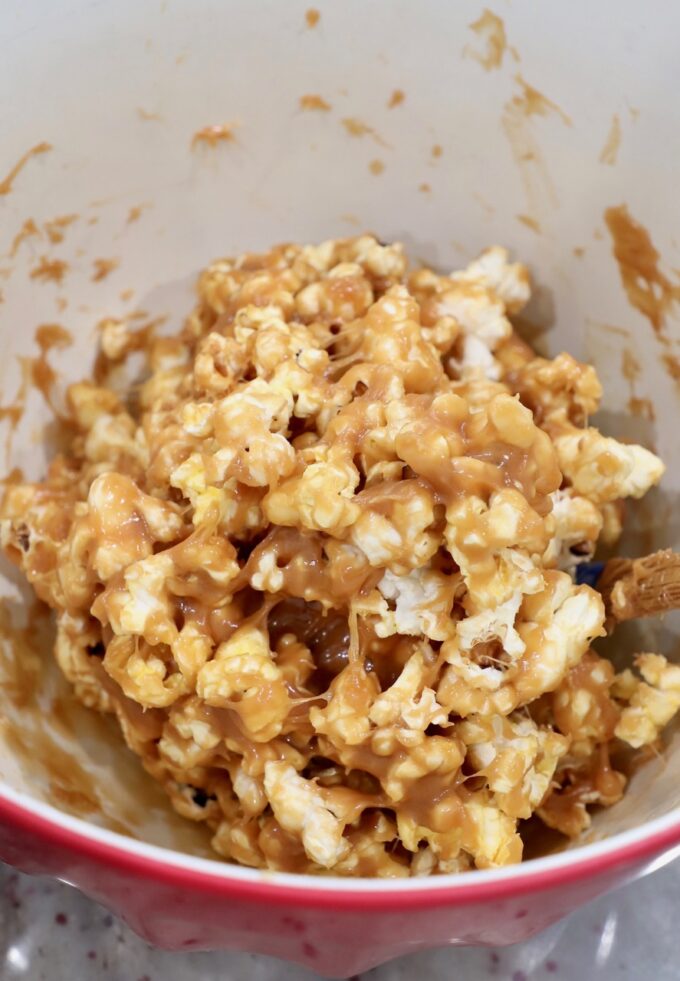peanut butter sauce tossed with popcorn in large bowl