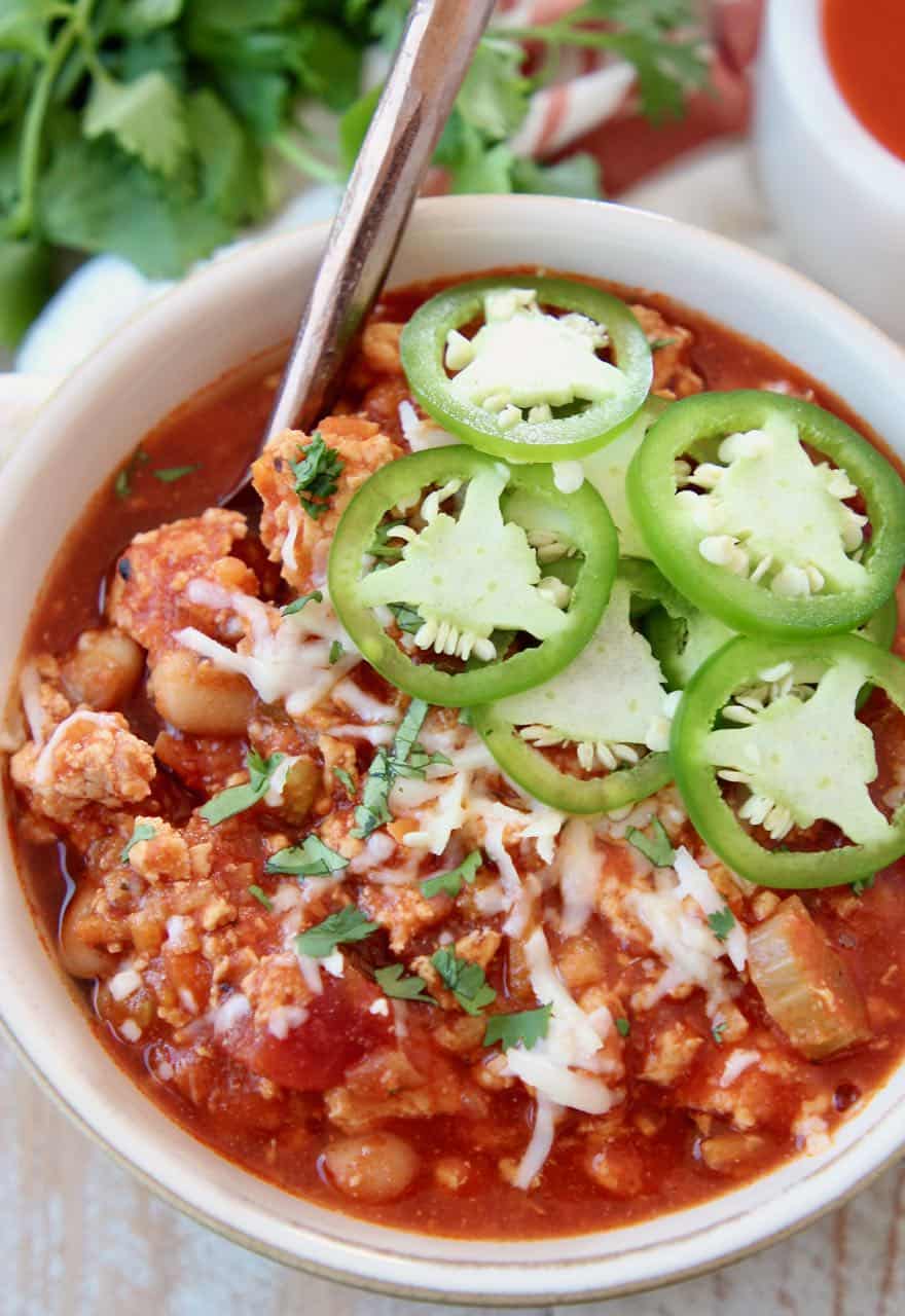 Buffalo chicken chili in bowl topped with fresh sliced jalapenos