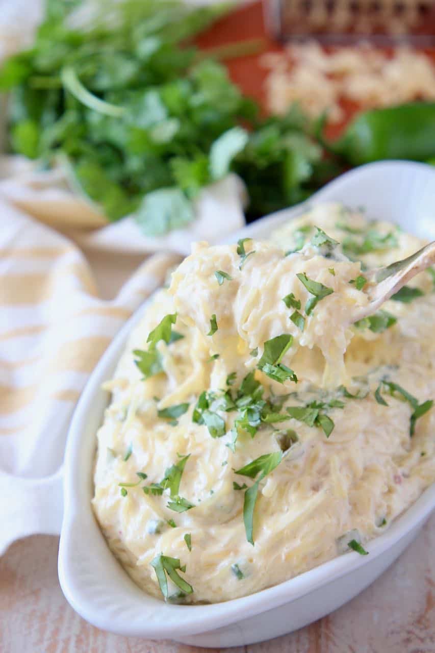 Fork coming out of bowl of roasted spaghetti squash with cheese sauce