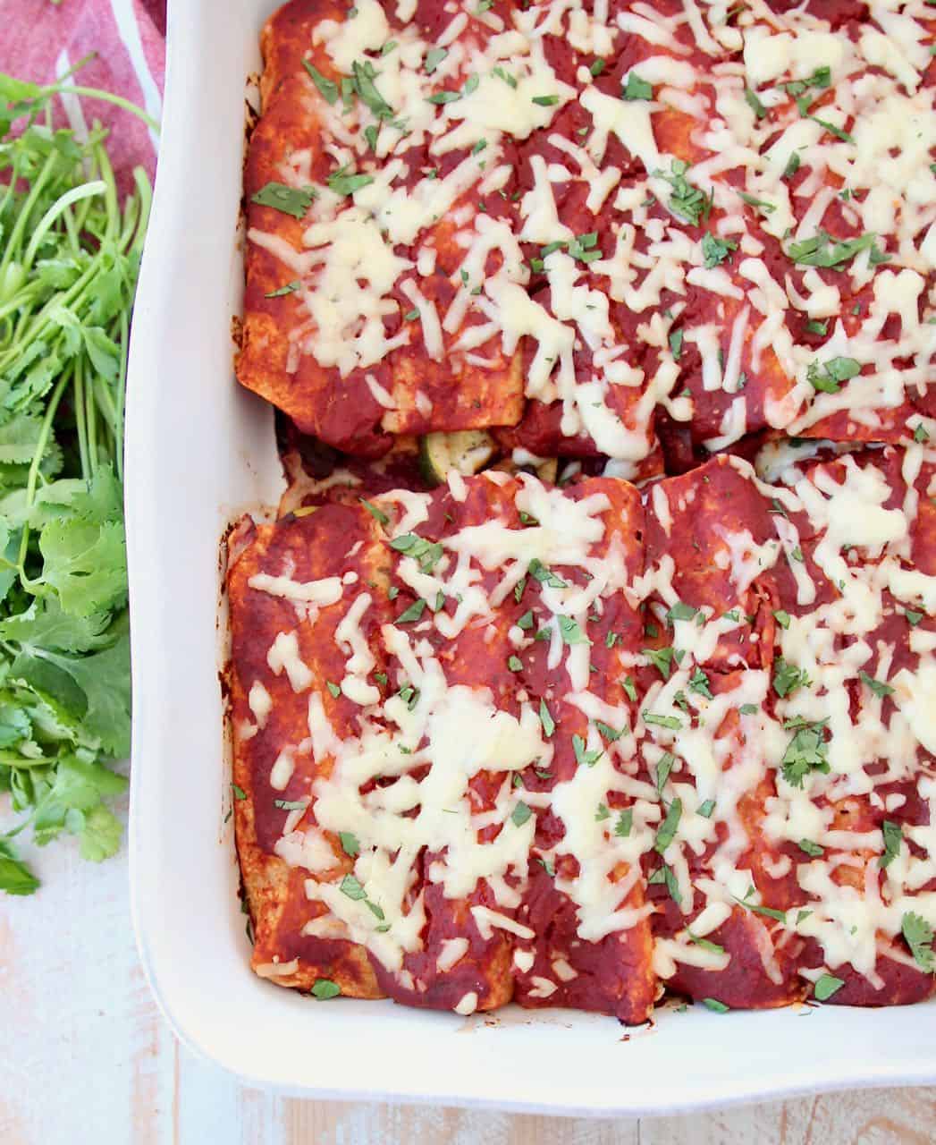 Enchiladas with red sauce in white casserole baking dish