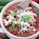 chili in a bowl with a spoon topped with grated cheese