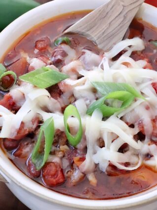 chili in a bowl with a spoon topped with grated cheese