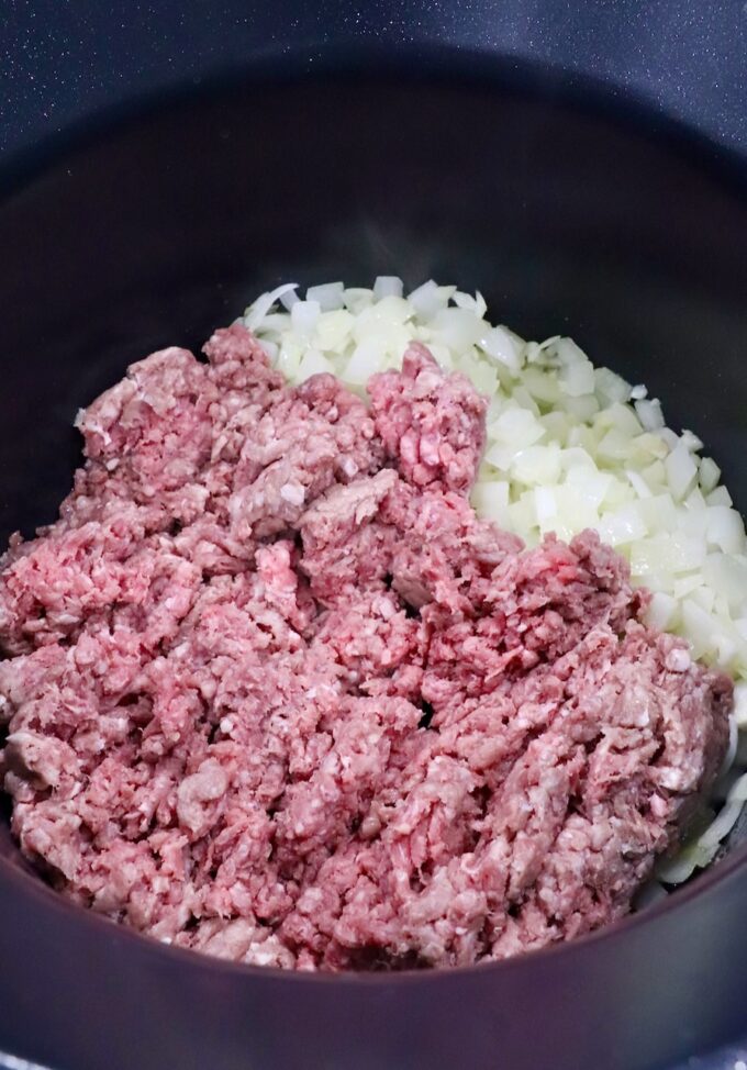 raw ground beef and diced onions in a pot