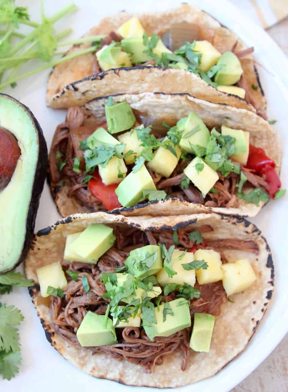 Three shredded tri tip tacos on plate with avocado