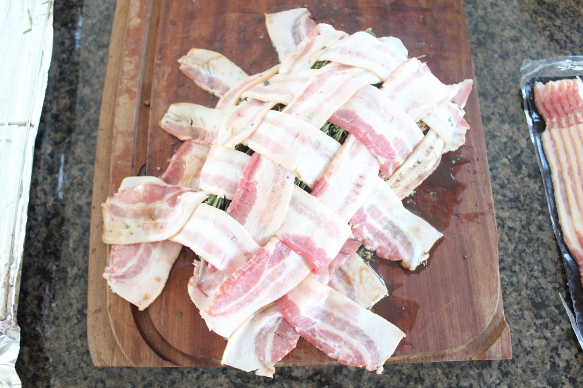 Bacon weave on top of turkey breast on wood cutting board