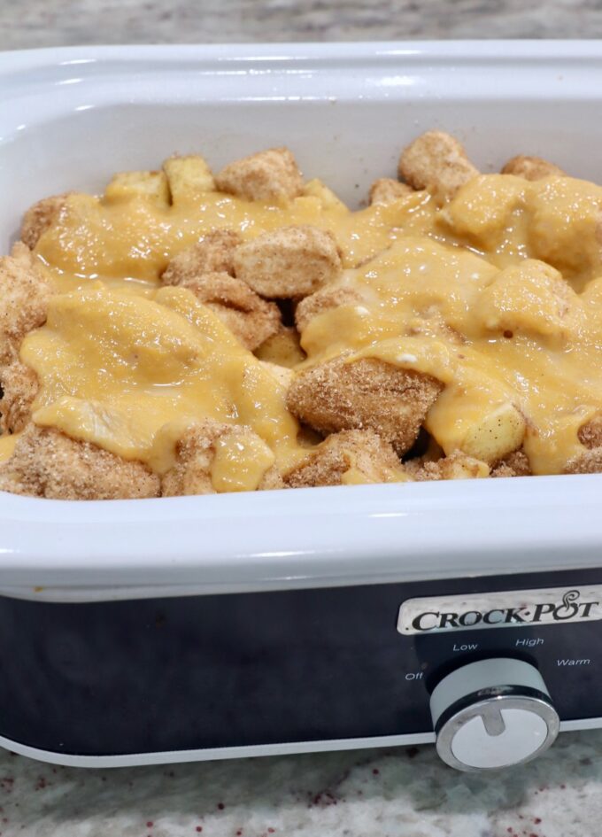 cinnamon sugar coated diced biscuit dough in crock pot topped with pumpkin puree