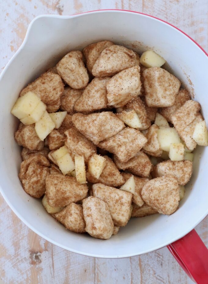 diced apples tossed with diced cinnamon sugar coated biscuit dough in mixing bowl