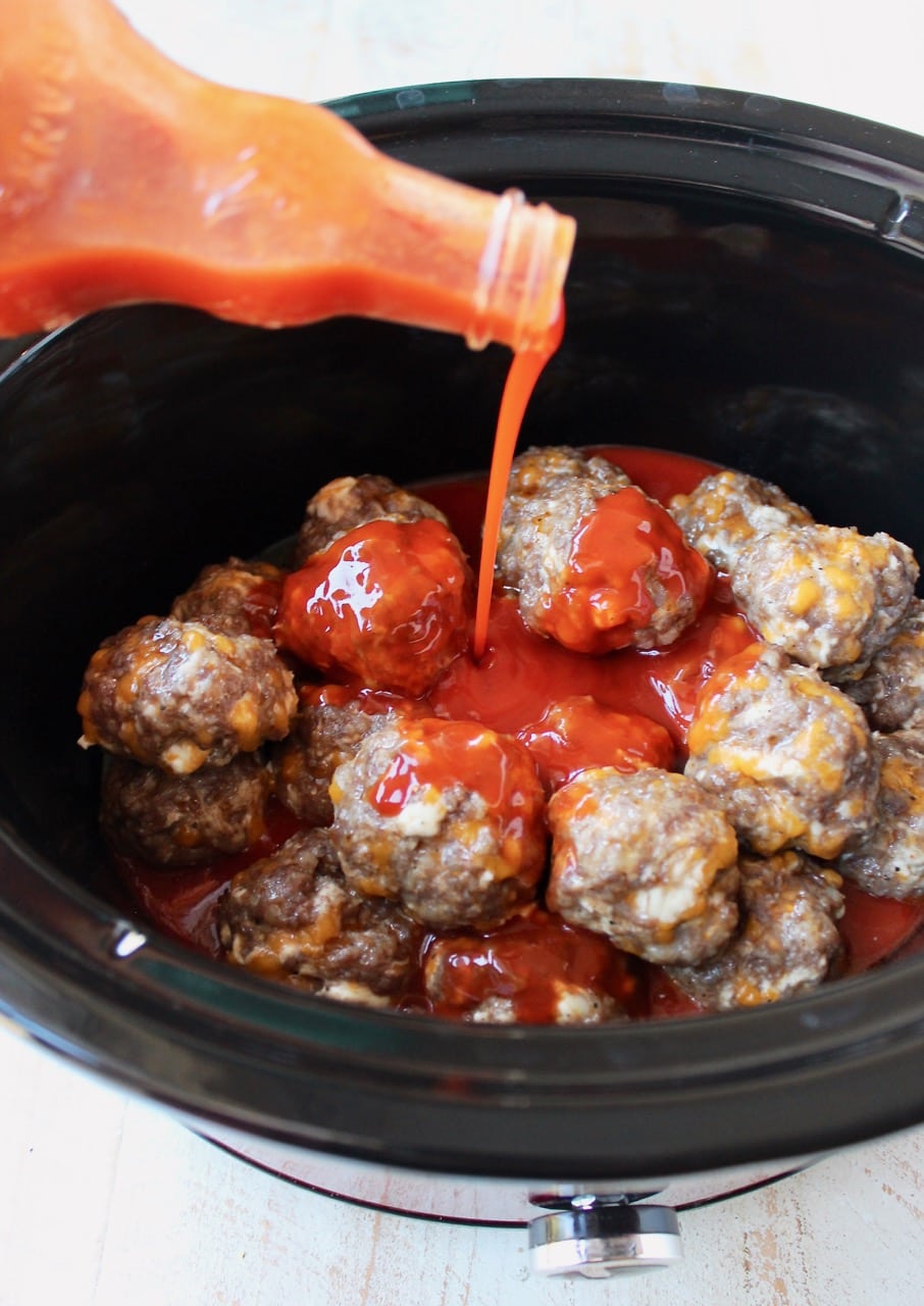 Cheesy Sausage Balls in Crock Pot with Buffalo Sauce Poured into the Crock Pot