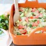Mexican casserole in orange baking dish with wooden spoon