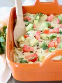 Mexican casserole in orange baking dish with wooden spoon