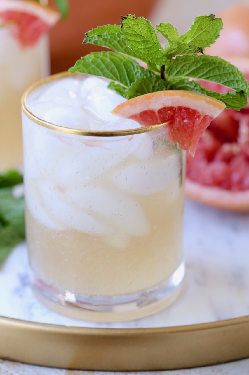 Grapefruit Ginger Rum Punch in glass with grapefruit slice on side and fresh mint in glass with ice