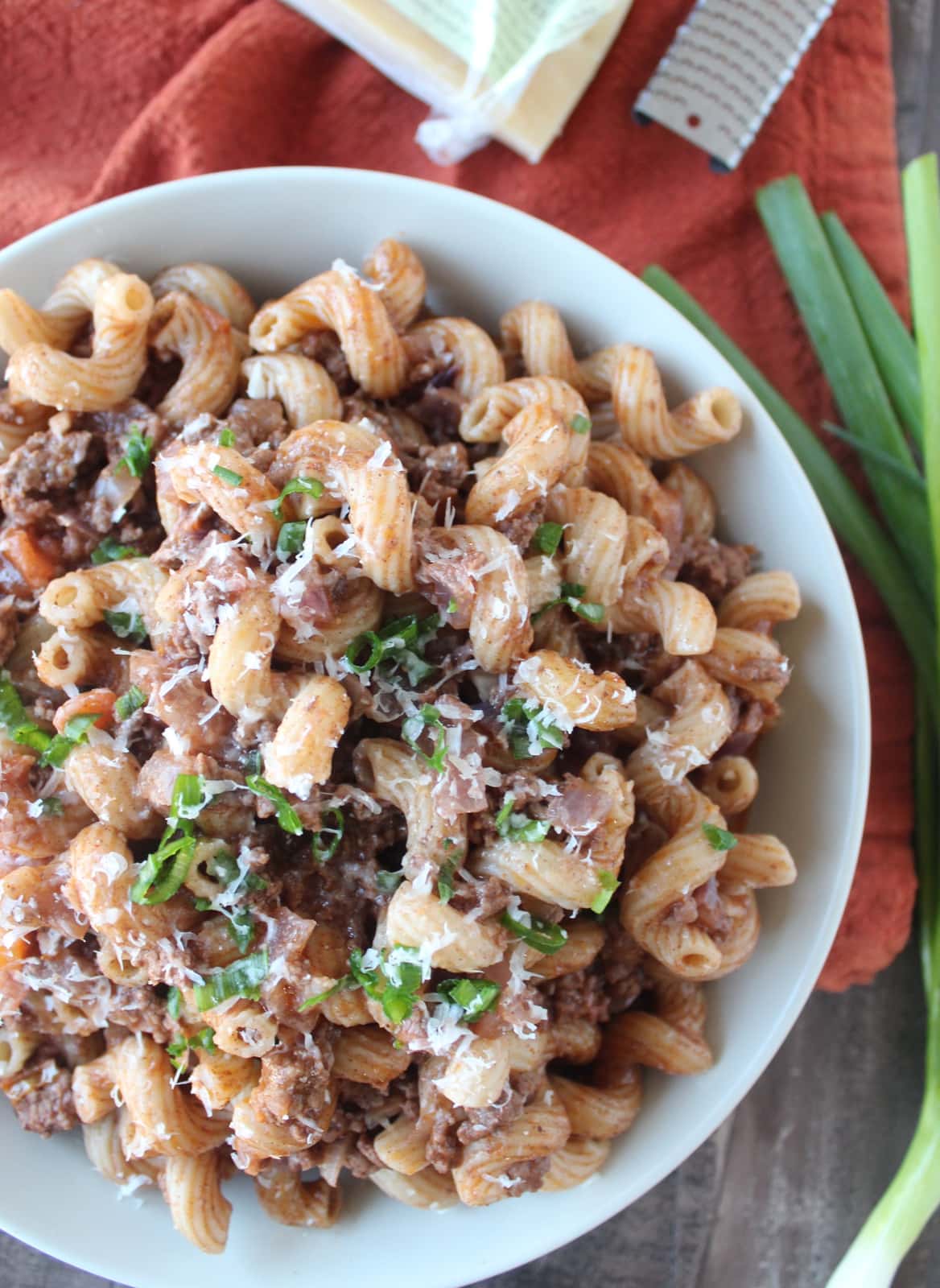 cooked pasta and ground beef in a bowl topped with parmesan cheese