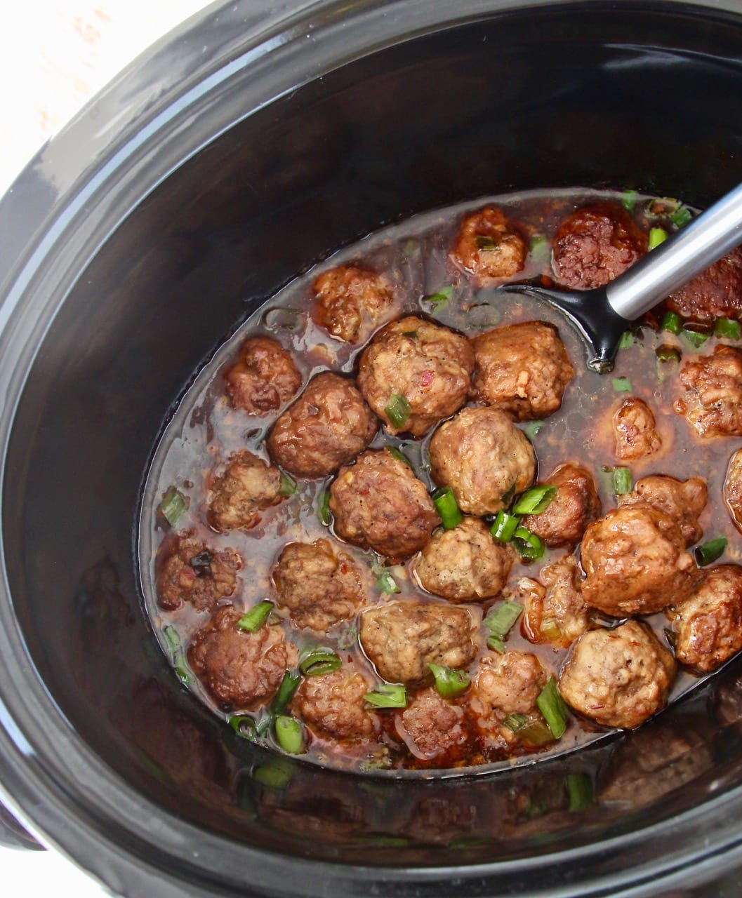 Korean meatballs in slow cooker with Korean BBQ sauce and serving spoon