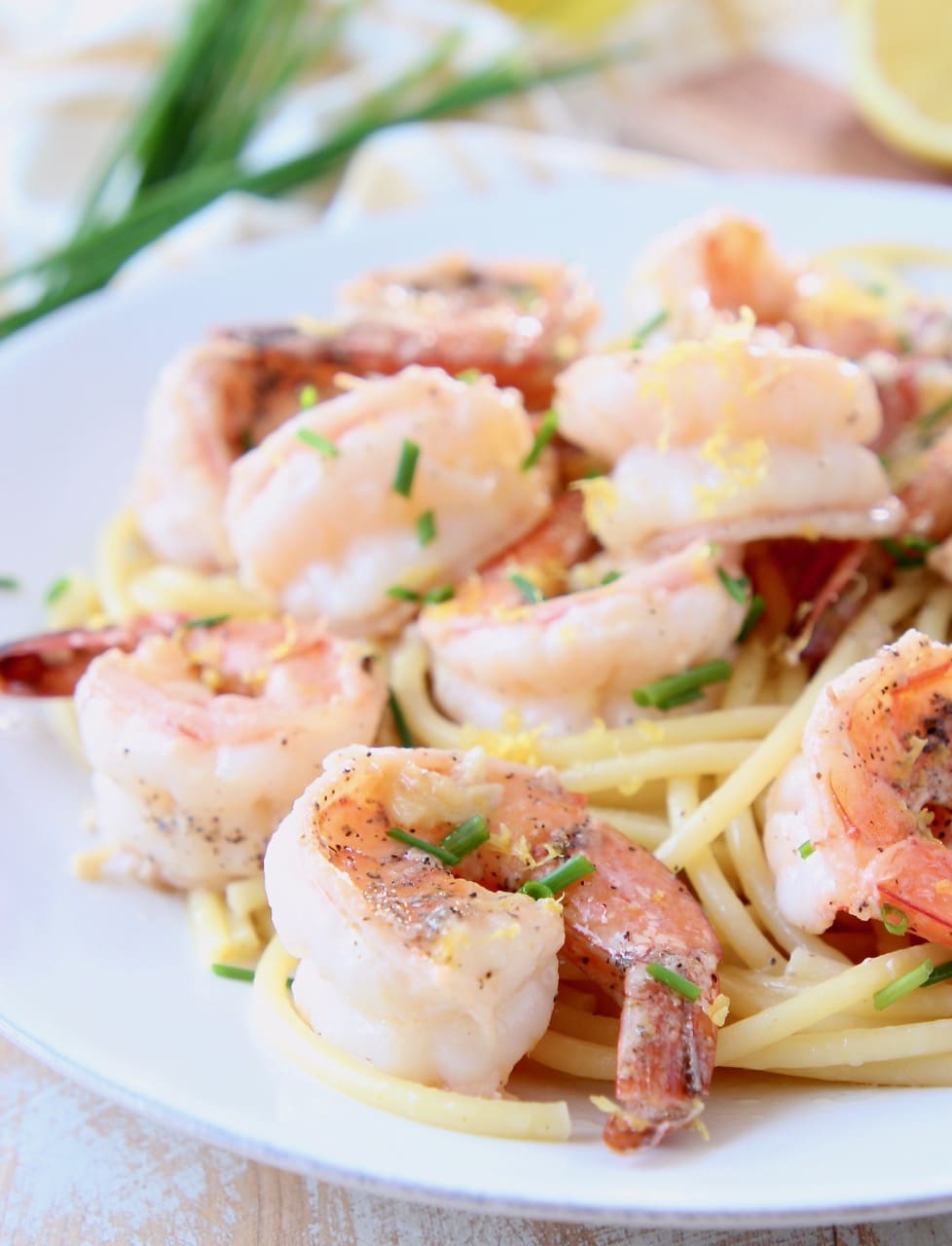 Shrimp scampi on top of bucatini pasta on white plate