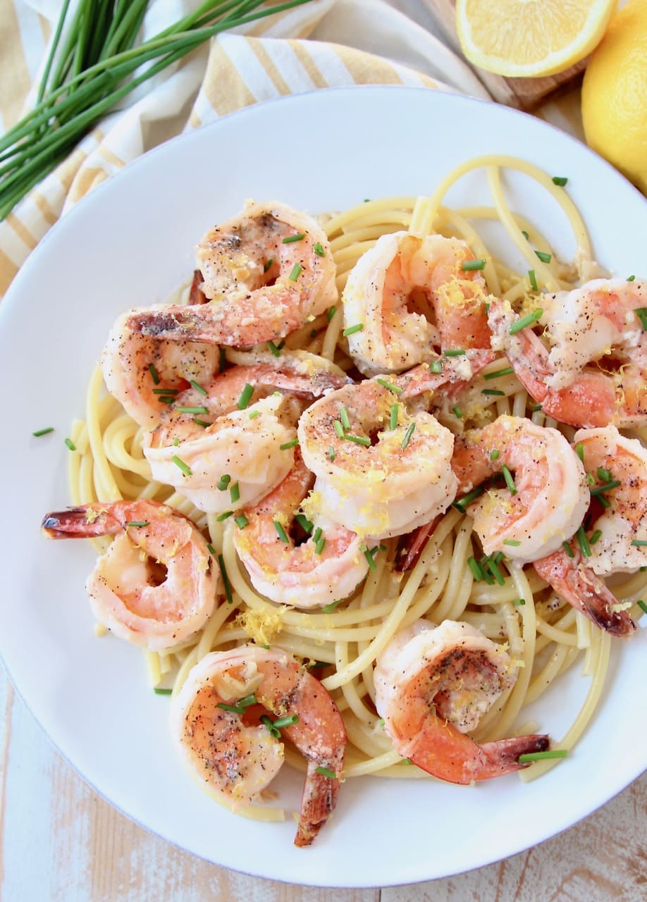 Overhead shot of shrimp scampi over cooked pasta on white plate