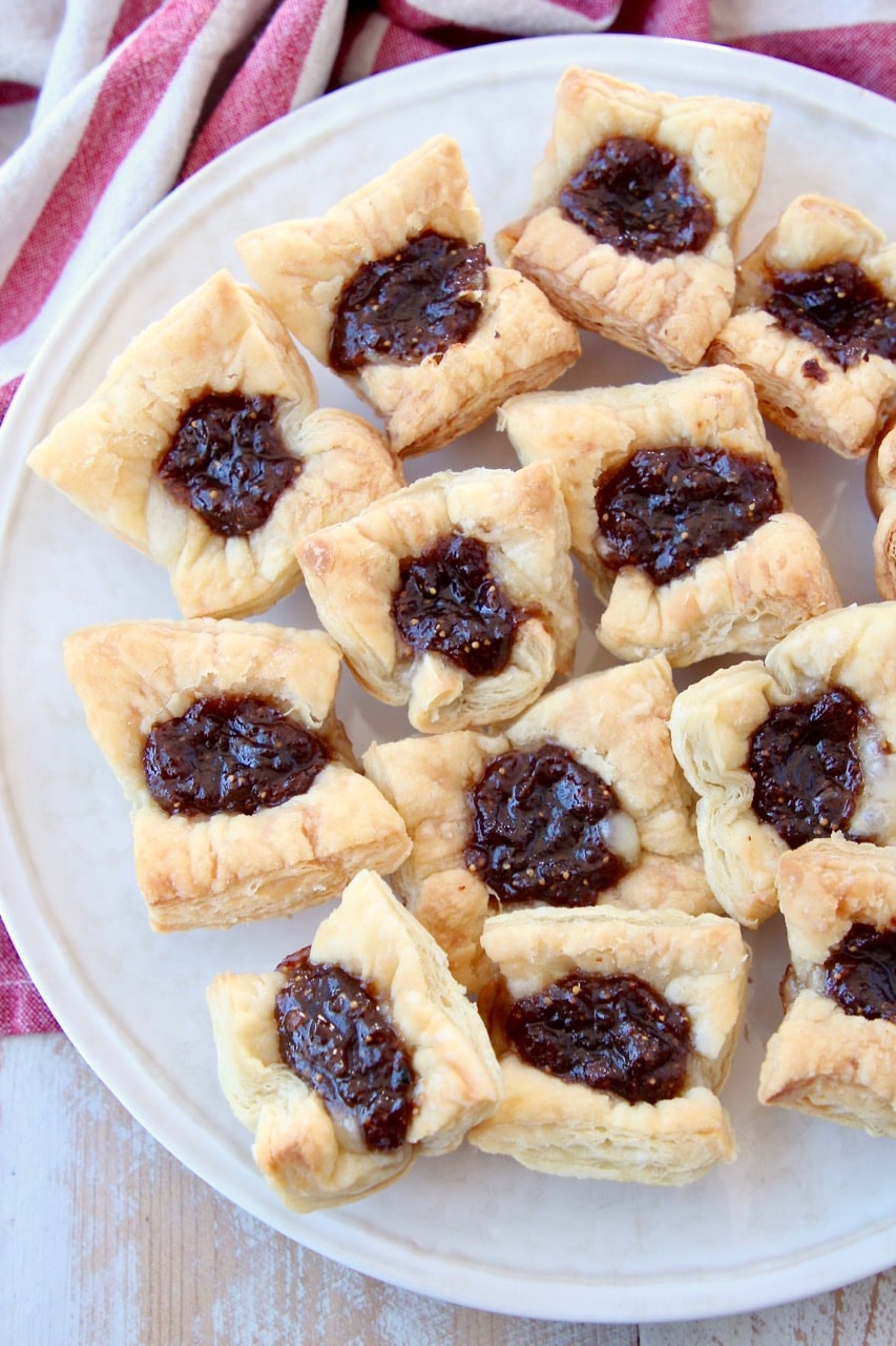 Baked puff pastry bites, filled with brie and jam, sitting on plate