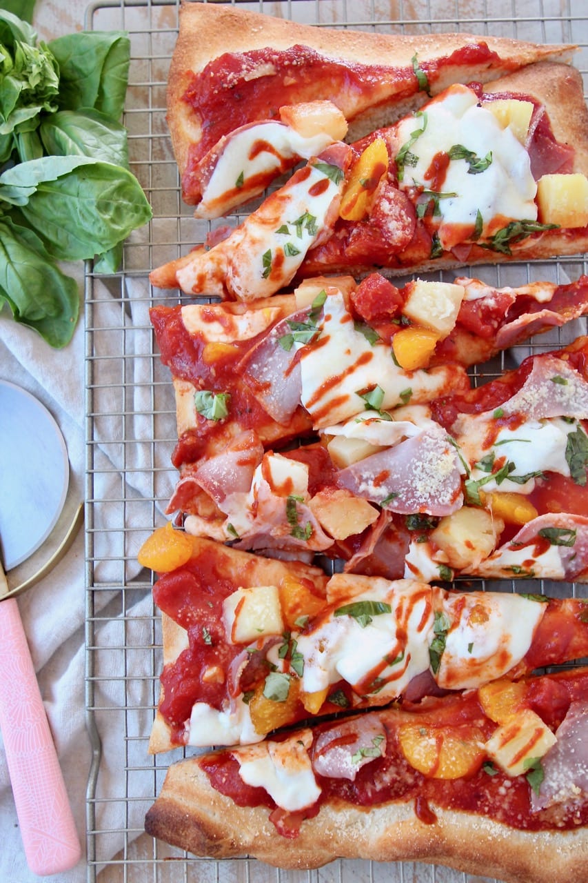 Hawaiian pizza sliced into pieces on wire baking rack