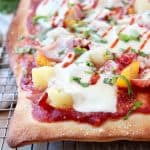 Hawaiian pizza on wire baking rack topped with pineapple, mandarin oranges and mozzarella cheese
