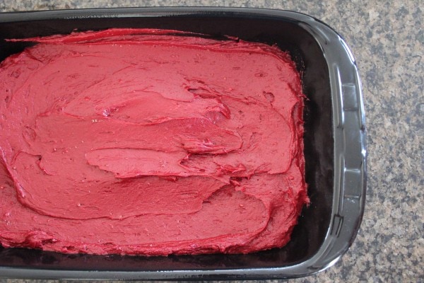 Red velvet brownie batter spread in the bottom of a baking dish.