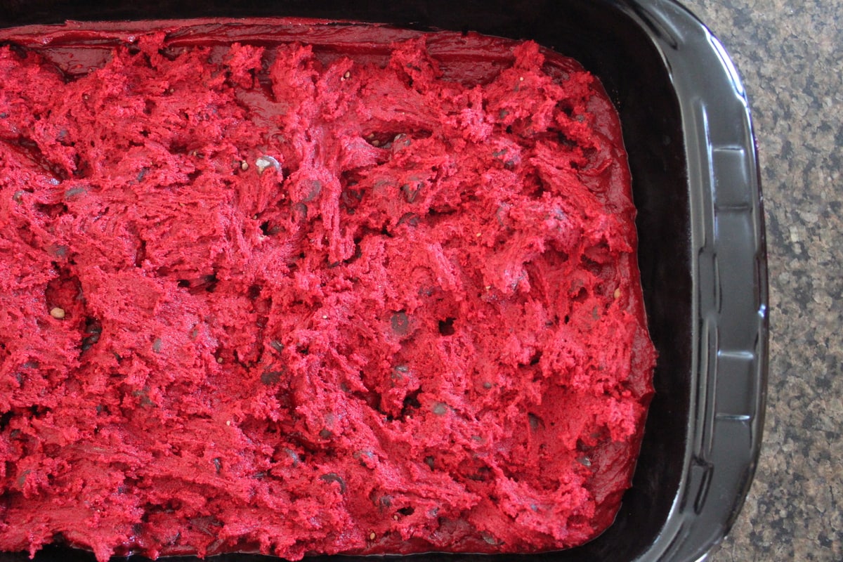 Brownie batter topped with red velvet cookie dough in a baking dish.