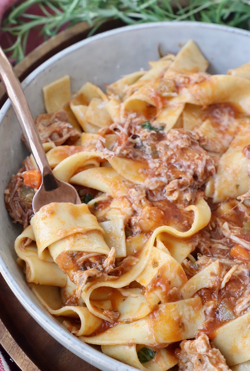 pasta stirred in fork in bowl with pork ragu sauce