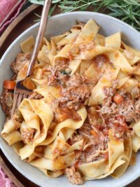 braised pork ragu tossed with cooked pasta in bowl with fork