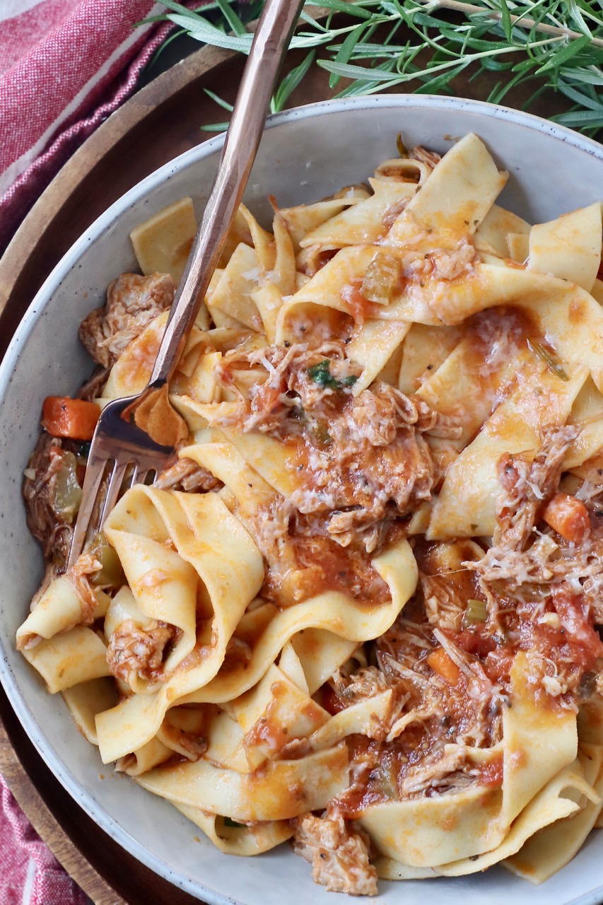 pork ragu sauce tossed with pappardelle noodles in bowl with fork