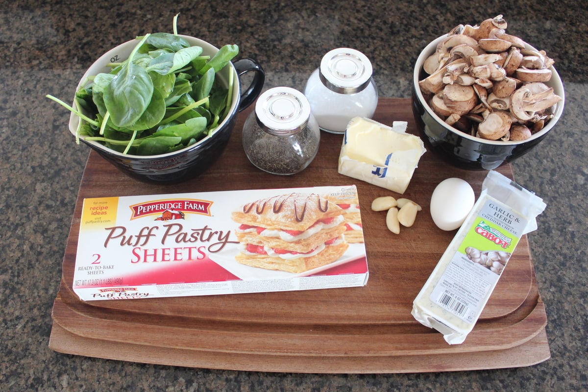 ingredients for mushroom spinach puff pastry on wood cutting board