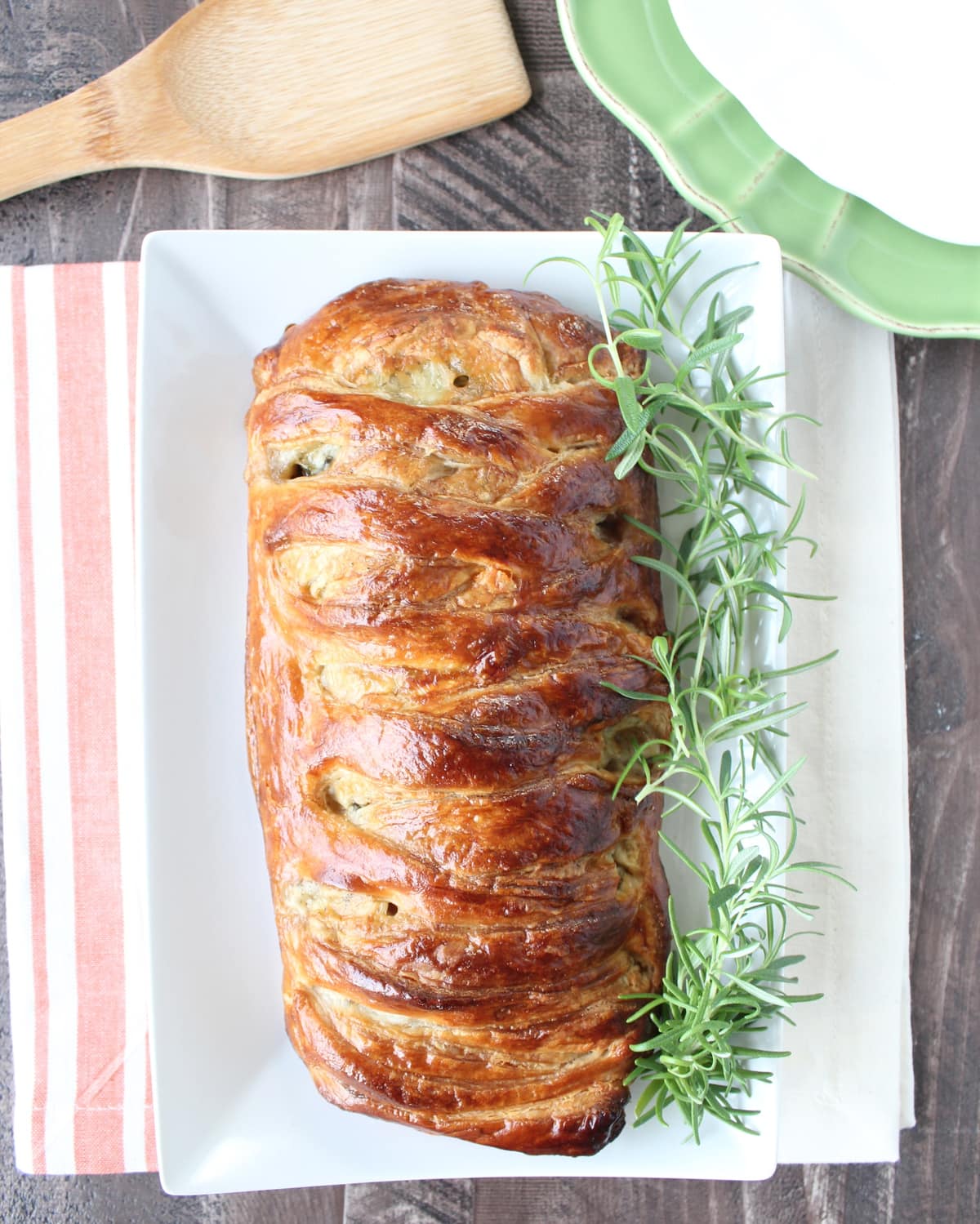baked braided filled puff pastry on plate with fresh rosemary