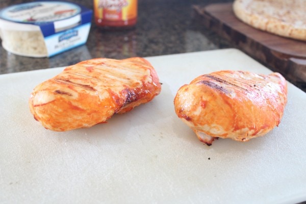 Two cooked chicken breasts resting on a white surface. 