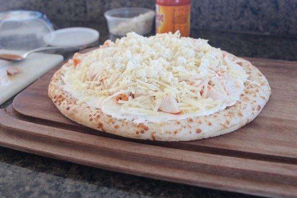 Uncooked Buffalo Chicken Dip Pizza on a wooden cutting board.