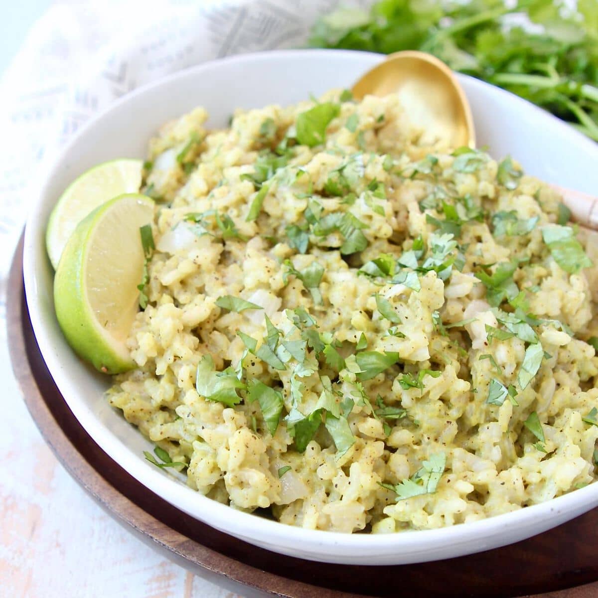 Pesto risotto in bowl with gold spoon and lime wedges