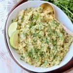 Cilantro pesto risotto in bowl with spoon and lime wedges