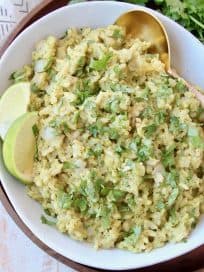 Cilantro pesto risotto in bowl with spoon and lime wedges