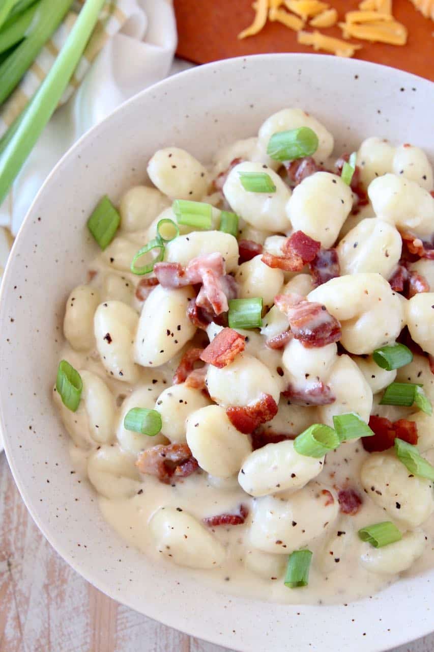 Overhead image of gnocchi in bowl with cream sauce and bacon bits