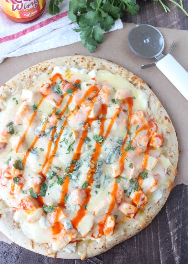 Buffalo Chicken Dip Pizza on a wooden surface next to a pizza cutter. 