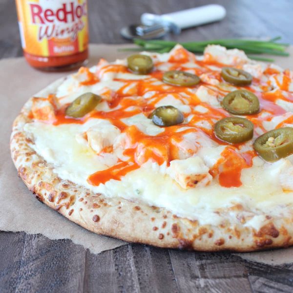 Pizza topped with melted cheese, chicken, buffalo sauce, and jalapeño slices. 