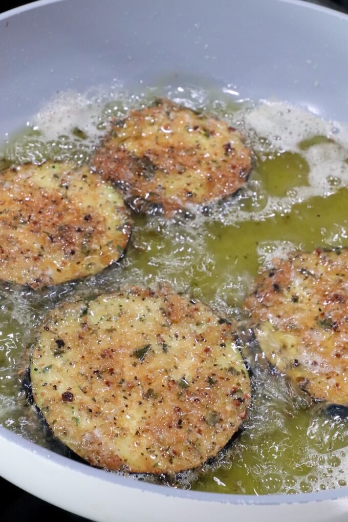 breaded slices of eggplant frying in oil in a pan