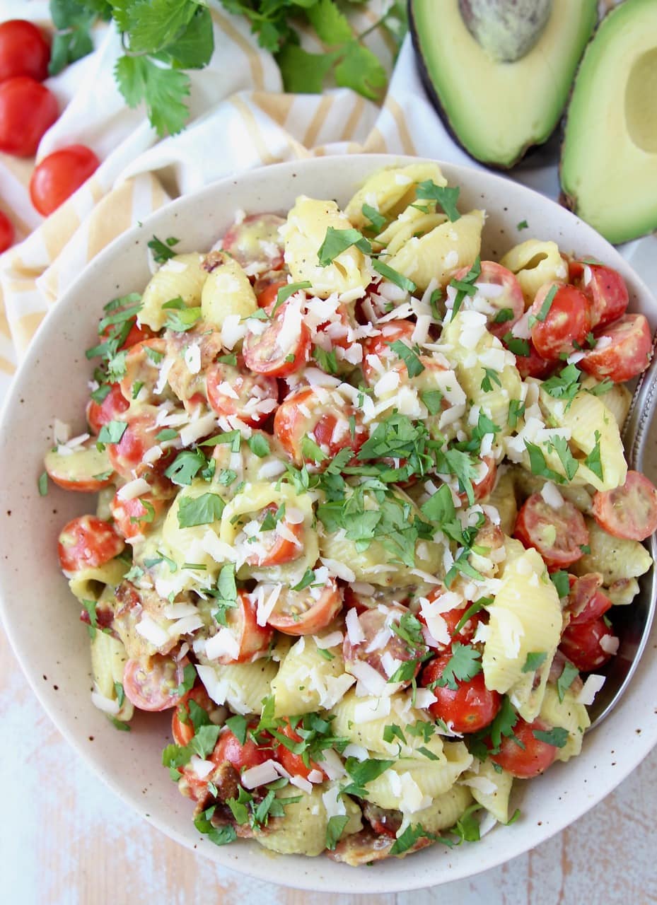 Overhead shot of BLT pasta salad in a bowl, topped with parmesan cheese and fresh basil