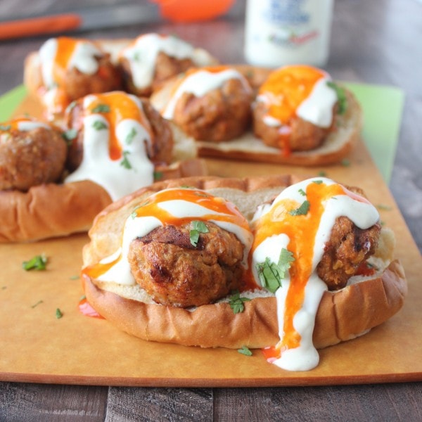 Hot dog bun topped with turkey meatballs and drizzled with buffalo sauce and blue cheese dressing.