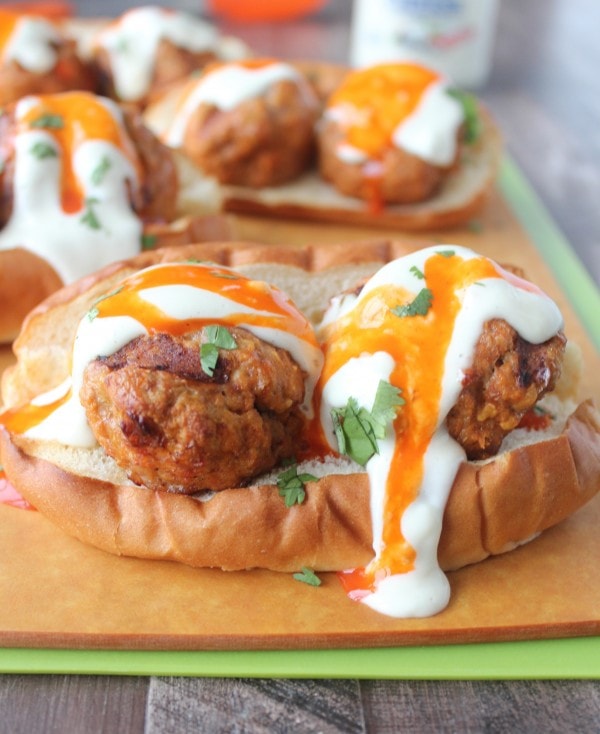 Hot dog bun topped with turkey meatballs and drizzled with buffalo sauce and blue cheese dressing.