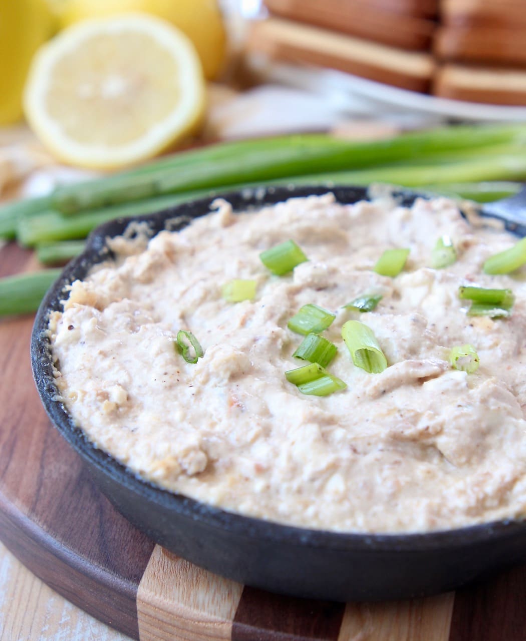 Hot crab dip in cast iron skillet, sitting on wood cutting board